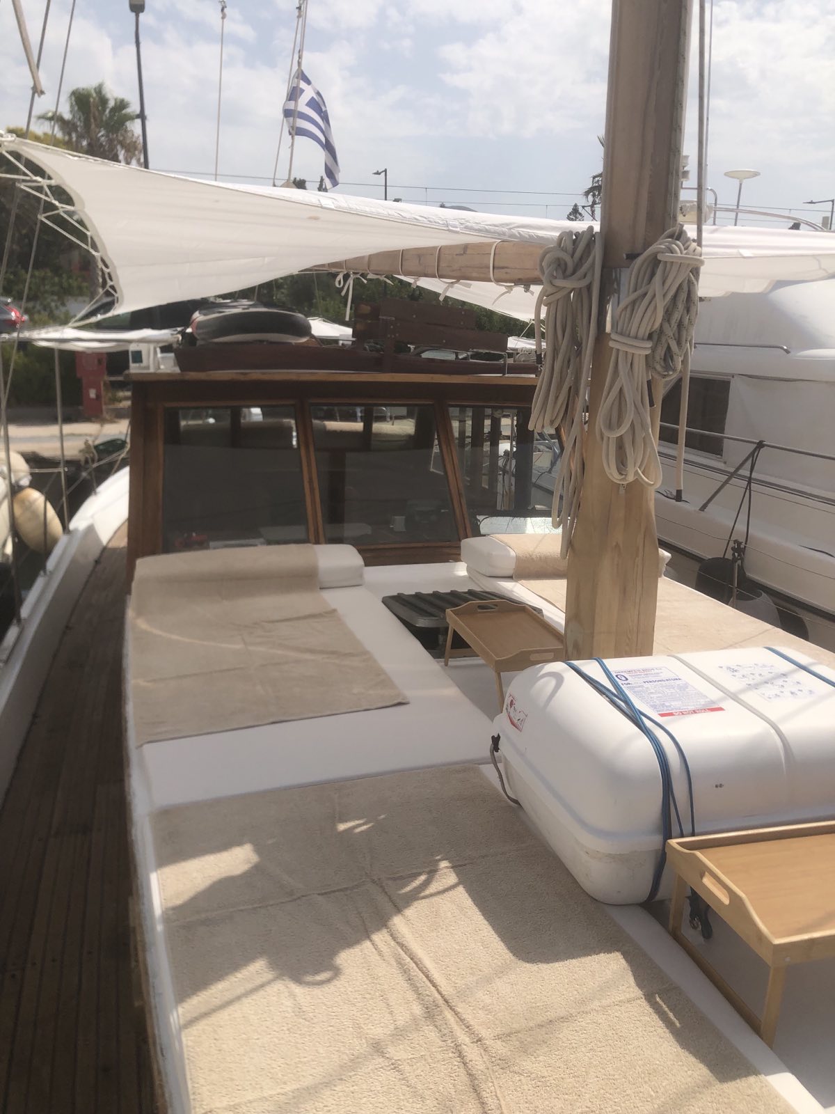 Cushioned foredeck with a canvas sun shade and coiled ropes on the mast
