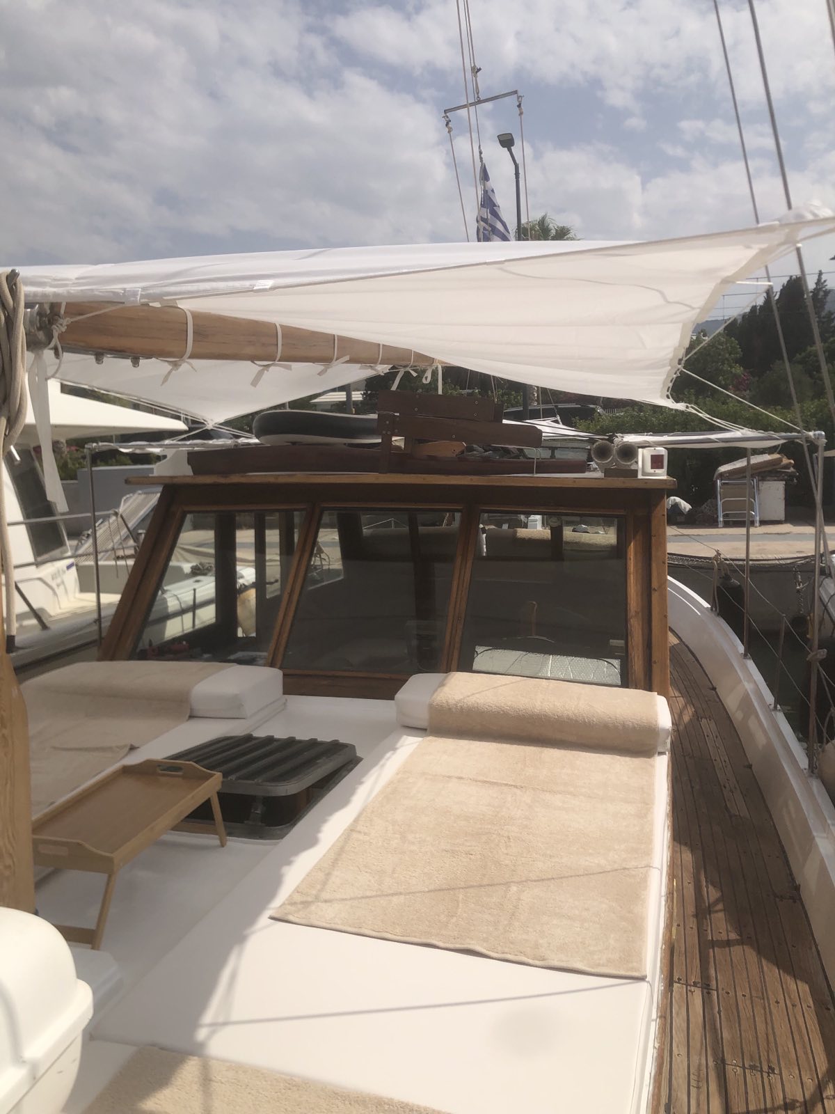 Wide cushioned sunbed on the foredeck beneath a white canvas awning