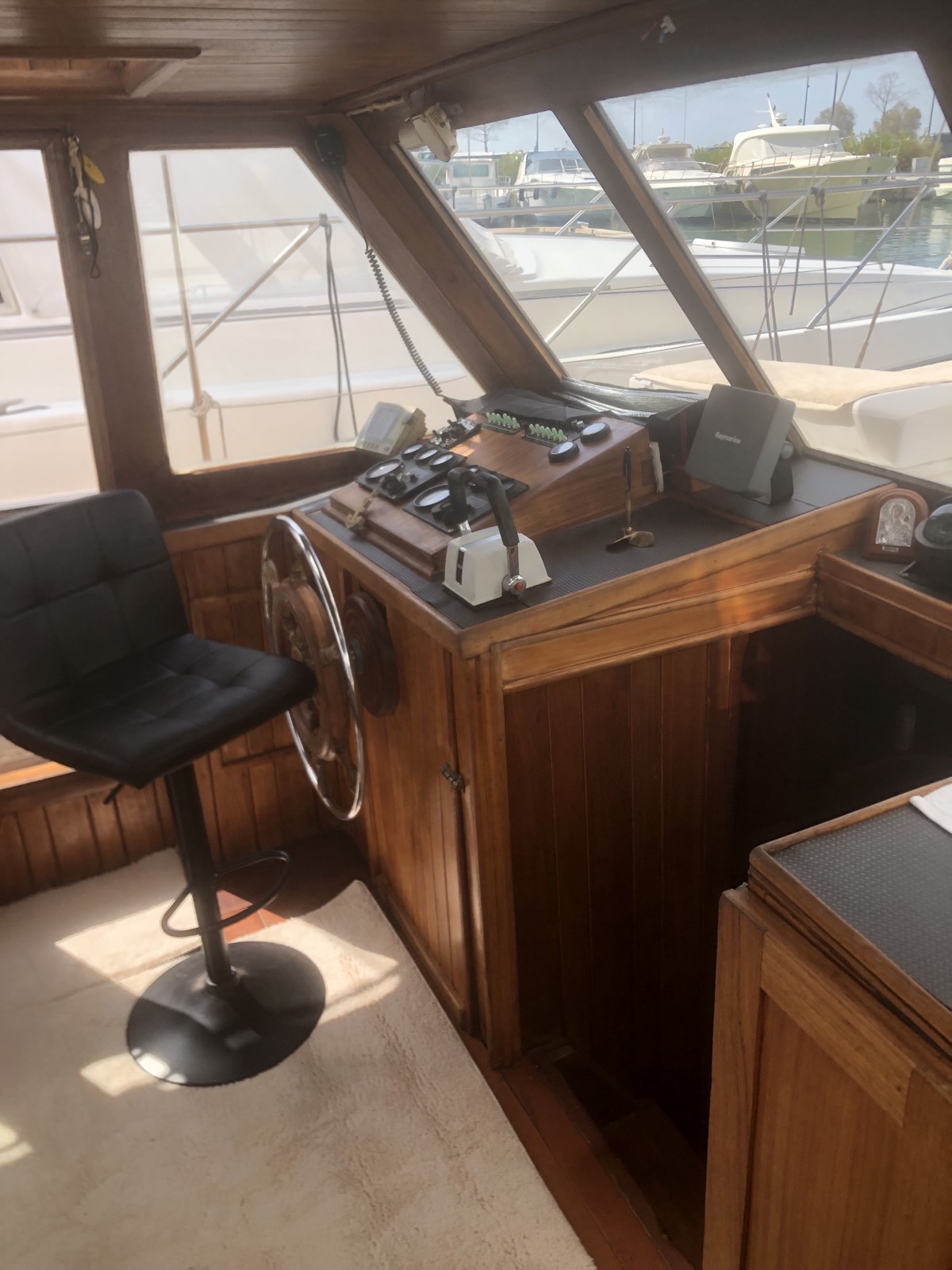 Wooden wheelhouse with a polished helm, instruments and a leather stool